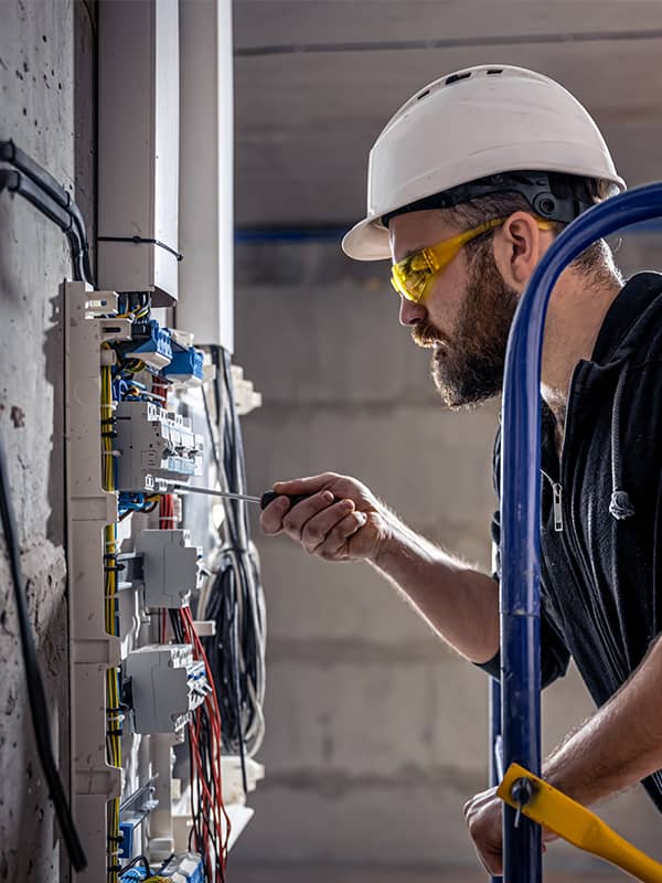 An electrician carefully screwing a device on a electric station