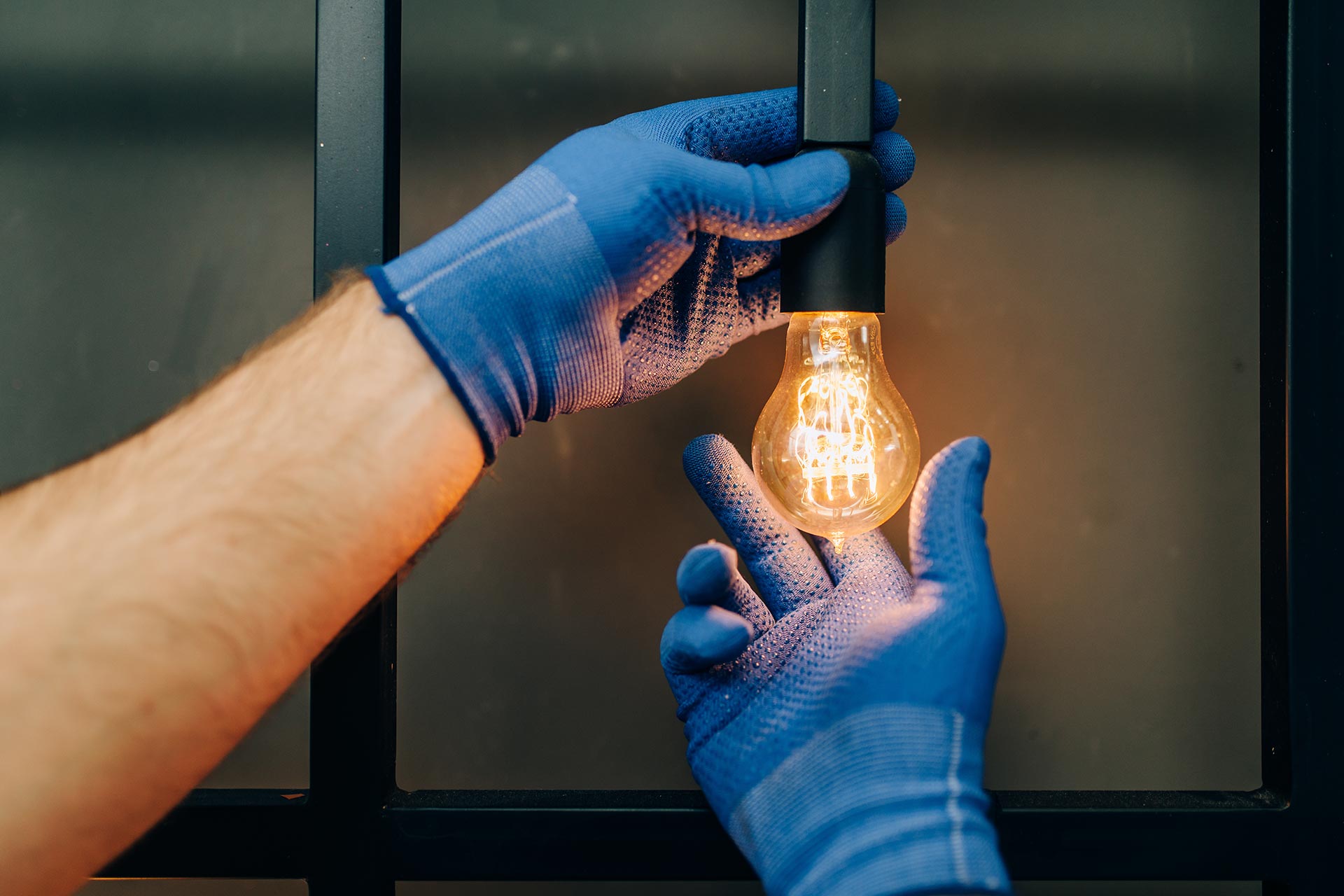 An image of two gloved hands checking the light bulb's light