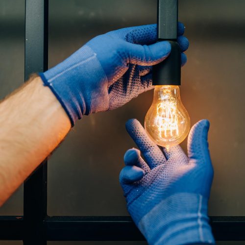 An image of two gloved hands checking the light bulb's light