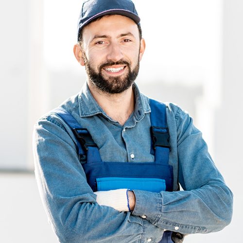 An uniformed electrician smiling while crossing his arms