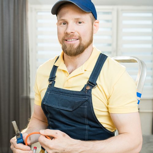 A smiling electrician trying to fix a wire cable